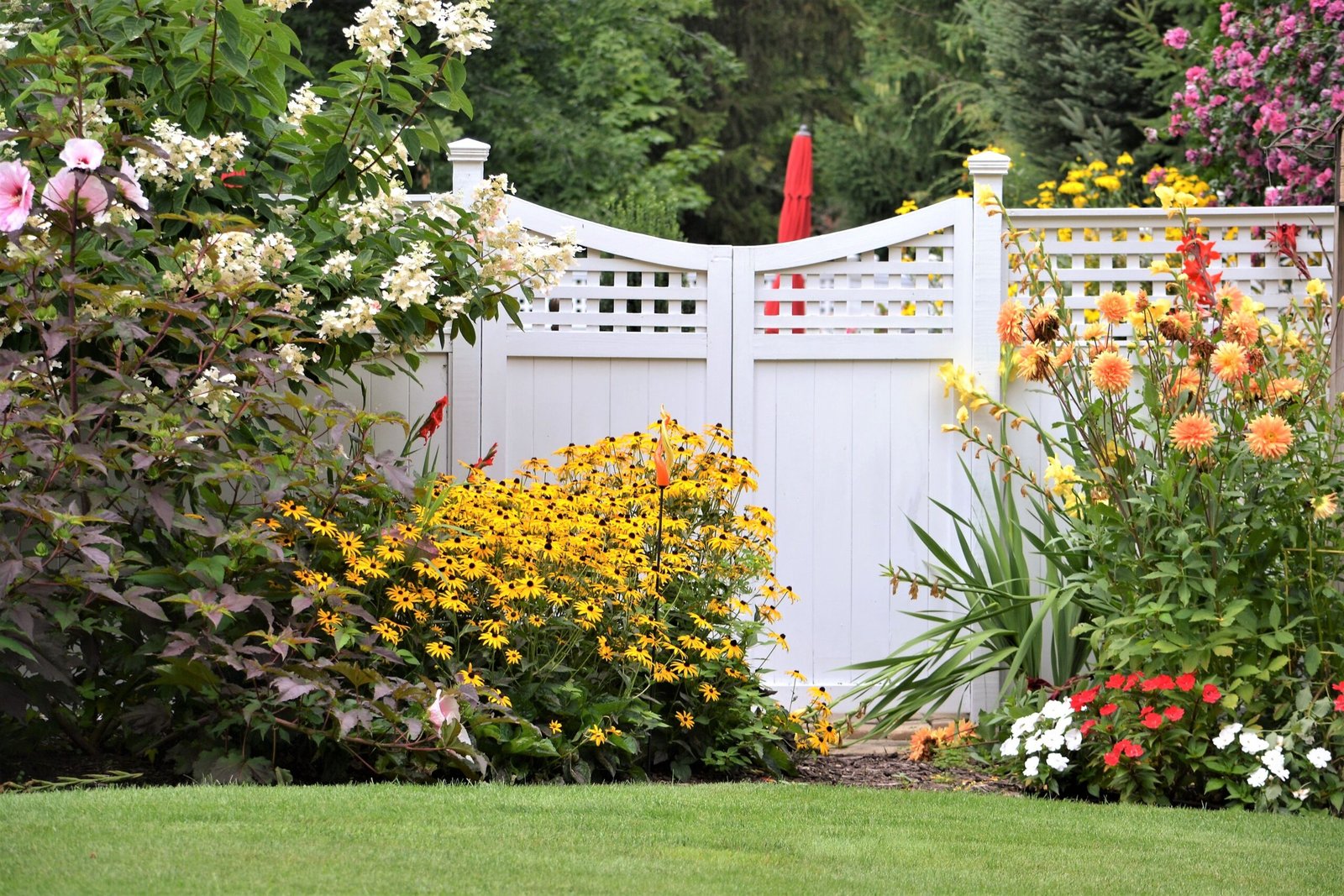 White vinyl fence with a colorful flower garden